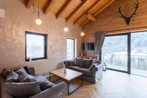 a living room with two couches and a table at CASA IL TRAMONTO Val di Sole in Commezzadura