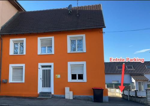 una casa arancione con una freccia rossa che punta verso un tetto arancione di Chambre climatisée et cosy Auberge du manala Hôtel 24 24 a Saint-Louis