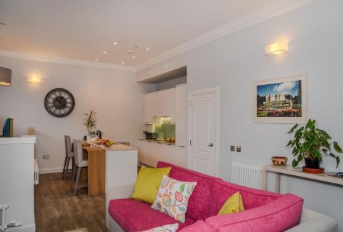 a living room with a pink couch and a kitchen at The Kinross Residence in Kinross