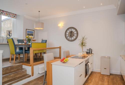 a kitchen and living room with a table and a clock on the wall at The Kinross Residence in Kinross