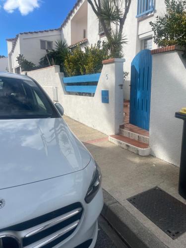 une voiture garée devant une maison avec une porte bleue dans l'établissement VILLA CANET EN ROUSSILLON, à Canet
