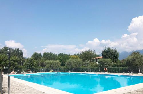 een groot blauw zwembad met bergen op de achtergrond bij La Maison du Port - Apartment with Pool in Manerba del Garda