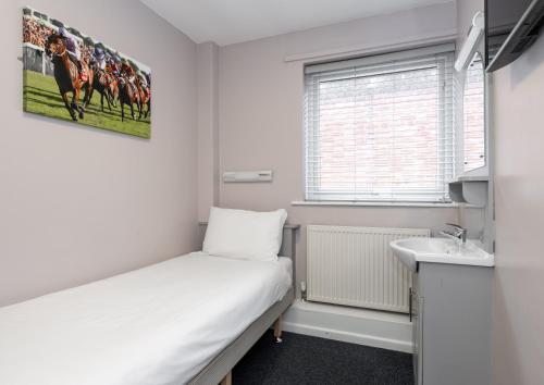 a small room with a bed and a sink at Stableside Hostel at York Racecourse in York