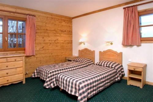 two beds in a room with wooden walls at Alpina Lodge - 02 - Appart rdc duplex - 8 pers in Les Deux Alpes