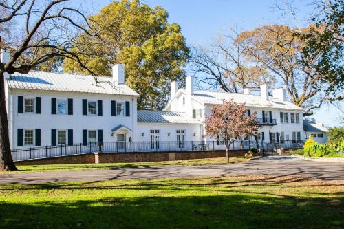 a large white house with a fence and trees at Excelsior at the Manor House in Clemmons