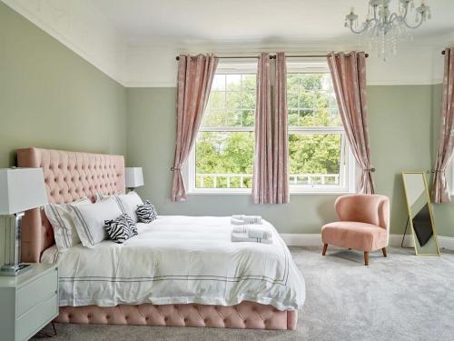 ein Schlafzimmer mit einem rosa Bett und einem rosa Stuhl in der Unterkunft Redrock House in Yelverton