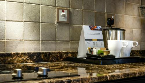 a counter top with a coffee maker and a cup at First Central Hotel Suites in Dubai
