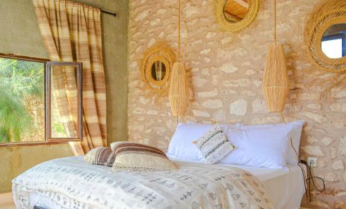 a bedroom with a bed and a stone wall at Villa Mama : comfort et hospitalité in Essaouira