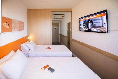 a hotel room with two beds and a flat screen tv at HUS Hotel MARINGA in Maringá
