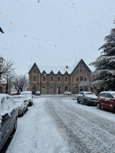 a snow covered street with cars parked in front of a building at Hotel Terminus in Puigcerdà
