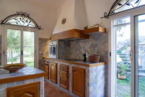 une cuisine avec des placards en bois et une grande fenêtre dans l'établissement Villa Santa Reparata di Balagna, à LʼÎle-Rousse