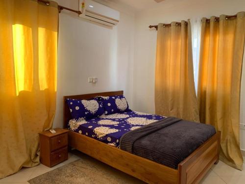 1 dormitorio con 1 cama con cortinas amarillas en The Greens Estate, en Madina