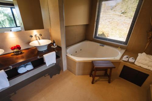 a bathroom with a tub and a sink and a bath tub at Loi Suites Chapelco Hotel in San Martín de los Andes