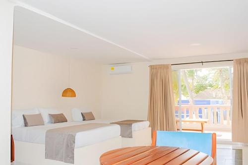 ein weißes Zimmer mit 2 Betten und einem Stuhl in der Unterkunft PLAYA PALMERAS PALMERAS BEACH RESORT in Cartagena de Indias