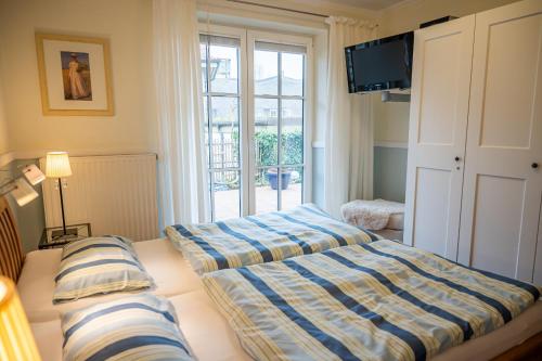 Un dormitorio con dos camas y un televisor y una ventana. en Birkenhof App 65 "Dünennest", en Wustrow