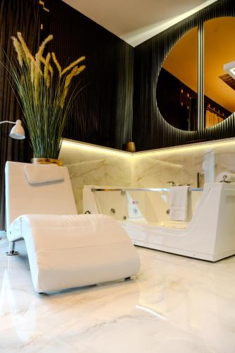 a bathroom with two white chairs and a mirror at Hotel Luxor in Lublin