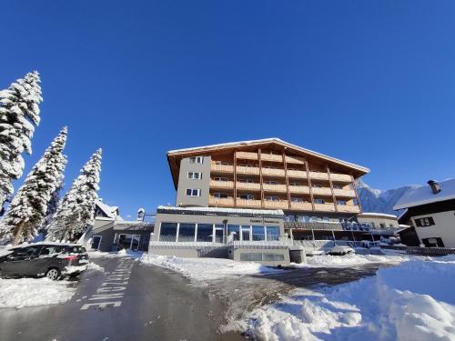 a large building with a parking lot in the snow at Zugspitz Residence Ehrwald in Ehrwald