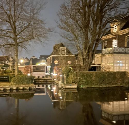a house on a canal at night at Koetshuis aan het water 3 bedroom villa in Voorburg