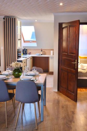 a dining room with a table and chairs and a door at Trón Apartman in Siklós