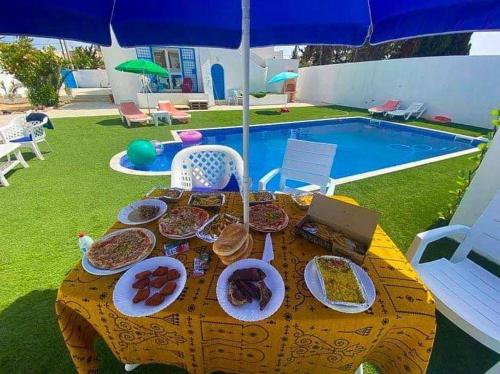 a table with plates of food on it next to a pool at Villa Sarah in Mezraya