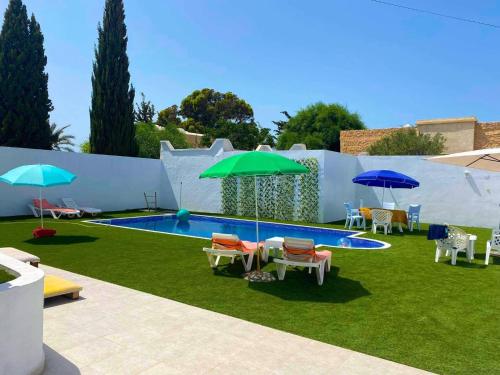 a backyard with a pool with chairs and umbrellas at Villa Sarah in Mezraya