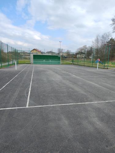 een lege tennisbaan met een gebouw op de achtergrond bij Apartamenty Pszczew Krzysztof Michna Lubuskie Mazury Apartament "MAJA" in Pszczew