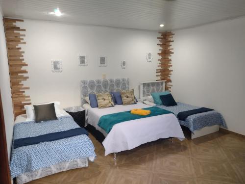 a bedroom with two beds and two chairs at LVL Hospedaje Ejecutivo in Ciudad del Este