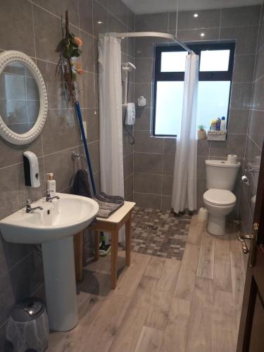 uma casa de banho com um lavatório, um WC e uma janela. em Home Comforts em Castleisland