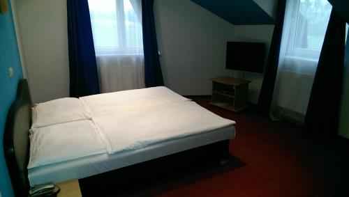 una camera da letto con un letto con lenzuola bianche e una TV di Casino & Pension Admiral Dolní Dvořiště a Dolní Dvořiště
