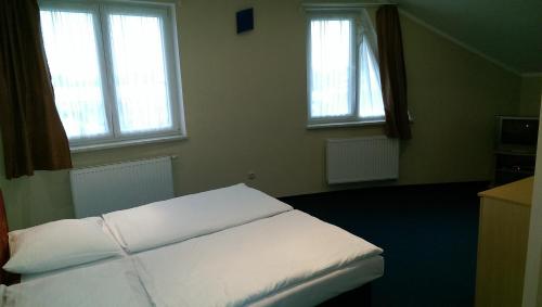 a bedroom with a white bed with two windows at Casino & Pension Admiral Dolní Dvořiště in Dolní Dvořiště