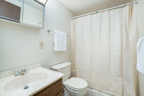Baño blanco con aseo y lavamanos en Wooded family-size Chalet with Fire pit & Hot tub!, en Hedgesville
