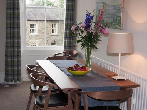 een tafel met een fruitschaal en een vaas met bloemen bij Stunning apartment in the centre of Corbridge in Corbridge