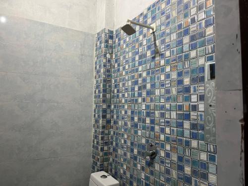 a bathroom with a blue tiled shower with a toilet at Priyakant inn in Vrindāvan