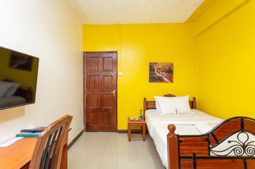 a bedroom with a bed and a yellow wall at Bonsai Villa in Nairobi
