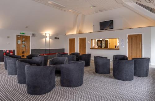 a waiting room with chairs and a tv on a wall at Stableside Hostel at York Racecourse in York