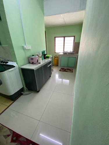 a kitchen with green walls and a white floor at Aziz homestay in Gemencheh