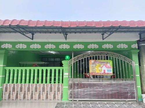 a green building with a gate in front of it at Aziz homestay in Gemencheh