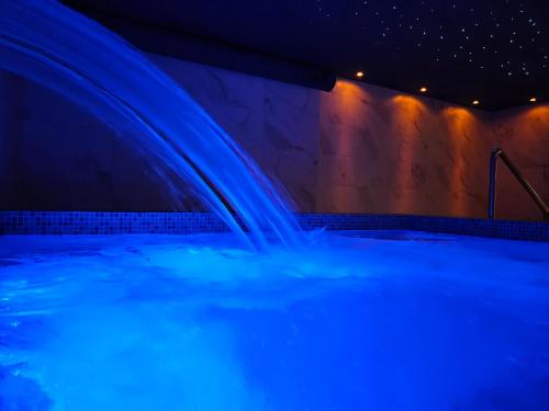 a swimming pool with a waterfall in blue lights at Hotel Wellness&Spa Astorya Banja Luka in Banja Luka