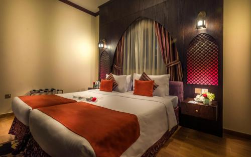 a hotel room with a large bed with orange pillows at First Central Hotel Suites in Dubai