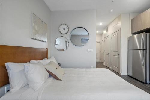 a bedroom with a large white bed and a refrigerator at CozySuites Modern SDO, Lawrenceville in Pittsburgh