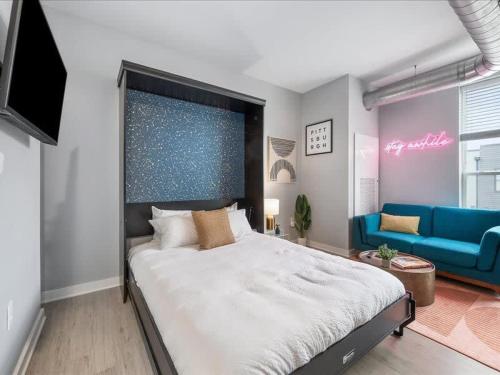 a bedroom with a large bed and a blue couch at CozySuites Boutique SDO, Lawrenceville in Pittsburgh