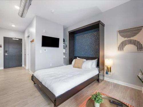 a bedroom with a large bed and a flat screen tv at CozySuites Boutique SDO, Lawrenceville in Pittsburgh