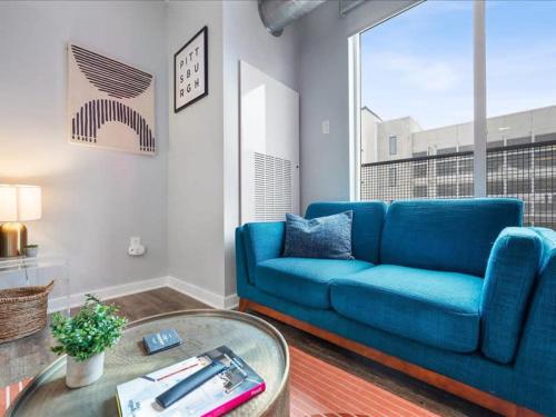 a living room with a blue couch and a table at CozySuites Trendy SDO, Lawrenceville in Pittsburgh