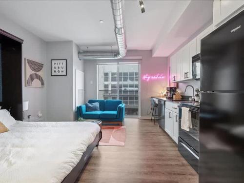 a bedroom with a bed and a kitchen with a blue chair at CozySuites Trendy SDO, Lawrenceville in Pittsburgh