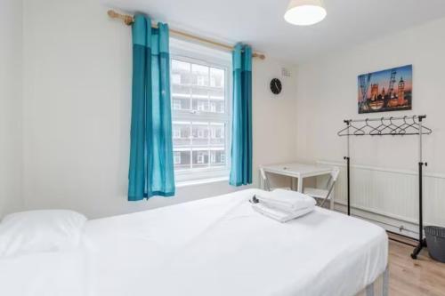 a bedroom with a bed with blue curtains and a window at APlaceToStay Central London Apartment, Zone 1 BOND in London