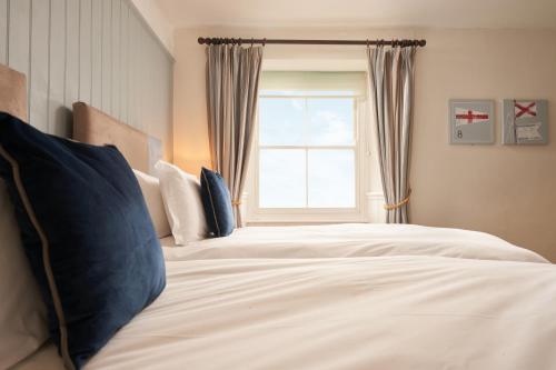 a bedroom with a large white bed with a window at Rashleigh Arms in St Austell