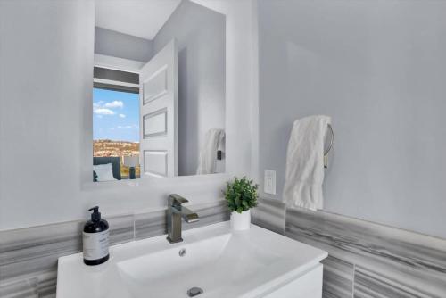 uma casa de banho branca com um lavatório e um espelho em CozySuites Spacious 2BR, PPG Paints Arena, Pitts em Pittsburgh