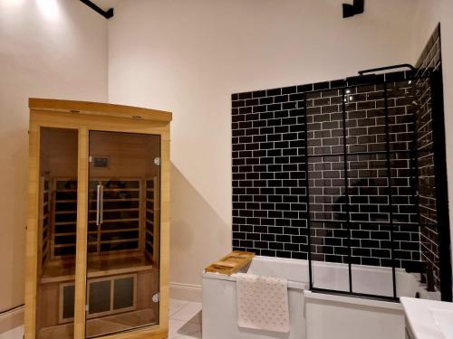 um quarto com um armário de vidro e uma parede de azulejos pretos em The Hamilton luxury holiday let's- Holly Barn em Scorton