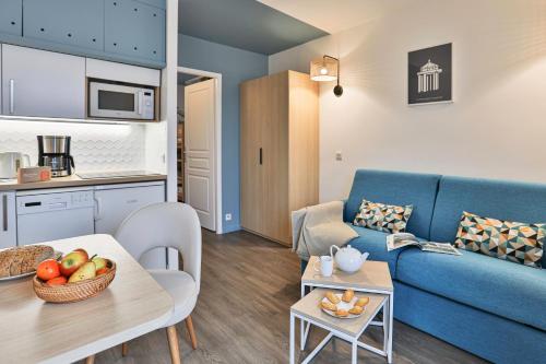 uma sala de estar com um sofá azul e uma mesa em Résidence Pierre & Vacances Centre em La Rochelle