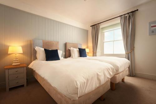 a bedroom with a large white bed with a window at Rashleigh Arms in St Austell